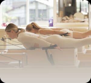 Vrouwen doen Pilates oefeningen op reformers in studio.