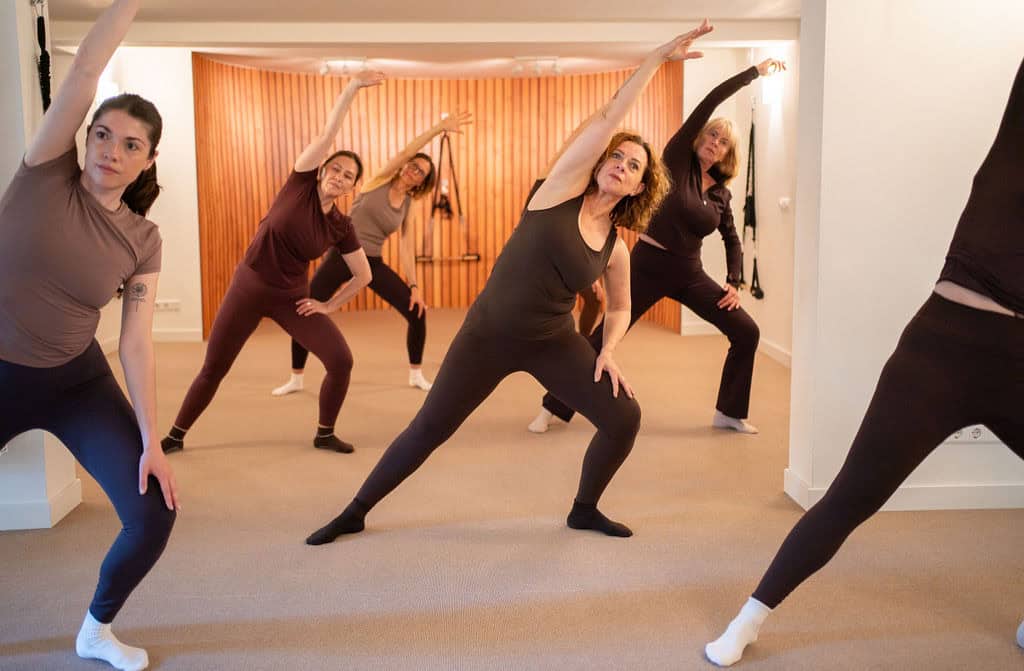 Groep vrouwen doet Essentrics oefening in studio, focus op flexibiliteit en kracht.