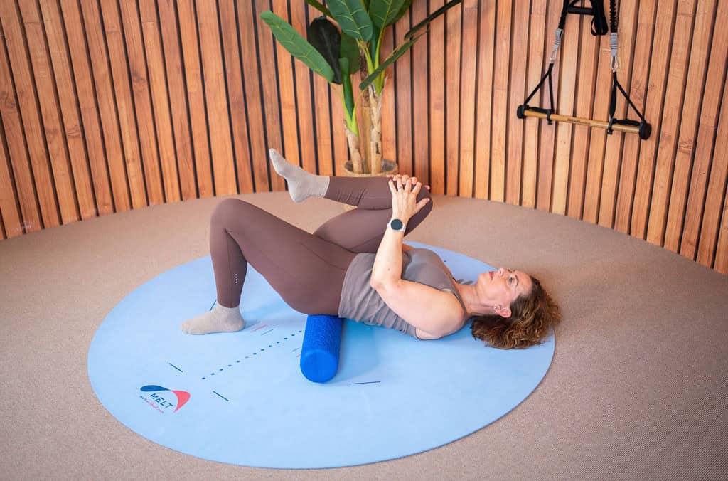 Persoon voert MELT-methode oefening met foam roller en yoga blok.